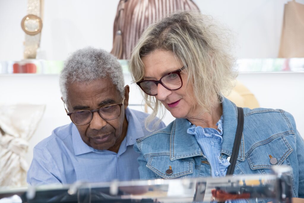 Two older adults browsing clothing together in a boutique.